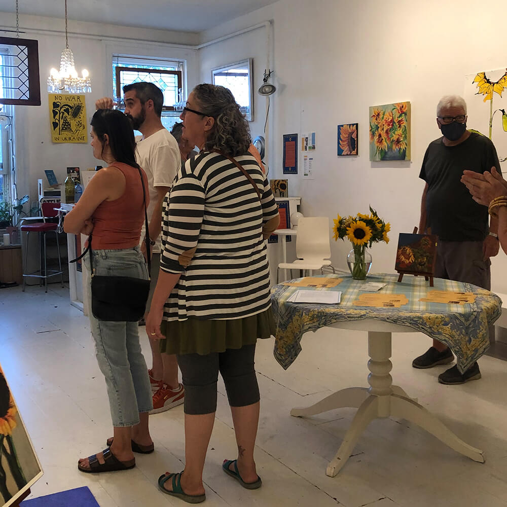 A crowd of people mingle in an artist's studio