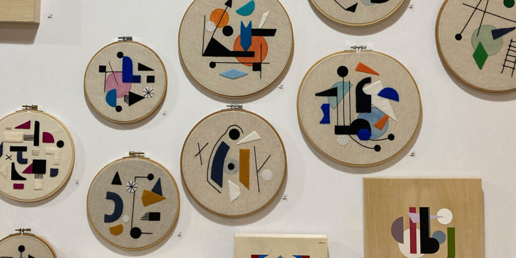Abstract textile work in embroidery hoops hangs on a wall